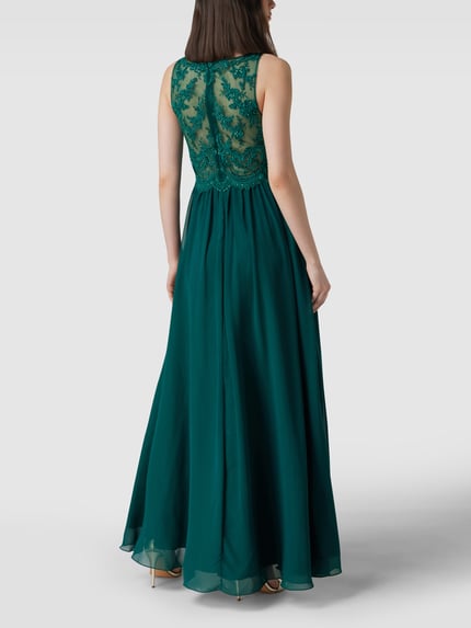 Männermodel trägt Regular Fit Abendkleid mit floralem Spitzenbesatz von Laona, zielony kolor, półprzezroczysty materiał, koronkowe zdobienia, okrągły dekolt, bez rękawów, kryształowe detale, podszewka kryjąca, widok całej sylwetki z tyłu.