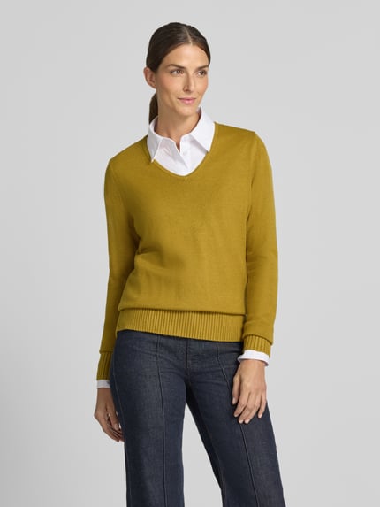 Frauenmodel trägt Regular Fit Sweatshirt aus Viskose-Anteil von Christian Berg Woman in Senfgelb mit V-Ausschnitt und gerippten Abschlüssen, Ganzkörperansicht von vorne. Kontext: Damen Sweatshirt aus Viskose-Mix, Regular Fit, Rückenlänge 63 cm, Ärmellänge 48 cm.