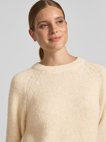 Vrouwenmodel draagt gebreide pullover met Raglanmouwen van FREE/QUENT, materiaalmix met wol, recht model, ronde hals, Nahaufnahme Oberkörper.