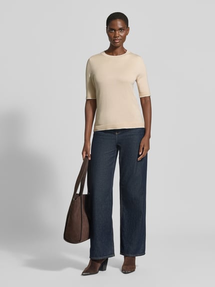 Frauenmodel trägt Regular Fit Pullover aus Viskose-Mix von s.Oliver BLACK LABEL in Beige, kombiniert mit dunkelblauer Hose, Ganzkörperansicht von vorne.