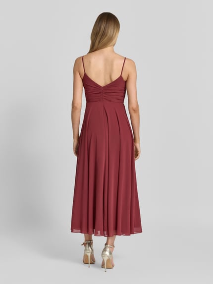 Frauenmodel trägt Cocktailkleid mit Drapierungen und Spaghettiträgern von Jake*s Cocktail aus Chiffon, Taillierter Schnitt, Midikleid, Ganzkörperansicht Rückansicht.