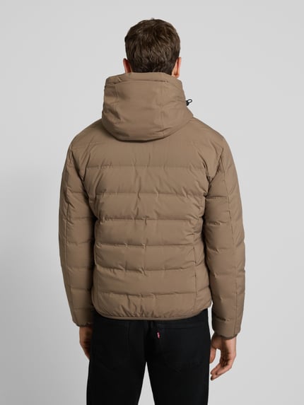 Męski model nosi Regular Fit Daunenjacke mit Kapuze od Marc O'Polo, jednokolorowy, elastyczne lamówki, wypełnienie z puchu i pierza, wodoodporna, wiatroszczelna, oddychająca, boczne wpuszczane kieszenie i kieszeń wewnętrzna, zdjęcie całej sylwetki od tyłu.