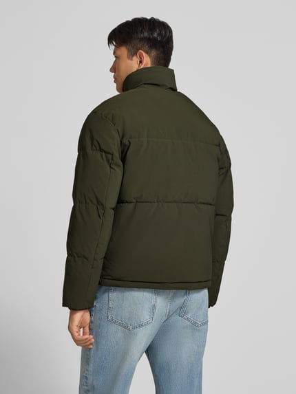 Männermodel trägt olivgrüne Steppjacke mit verdecktem Reißverschluss Modell 'SOHO' von JACK & JONES, Rückenansicht, Ganzkörperansicht. Rückenlänge, Schulterbreite, Brustweite und Ärmellänge gemäß Größe M.