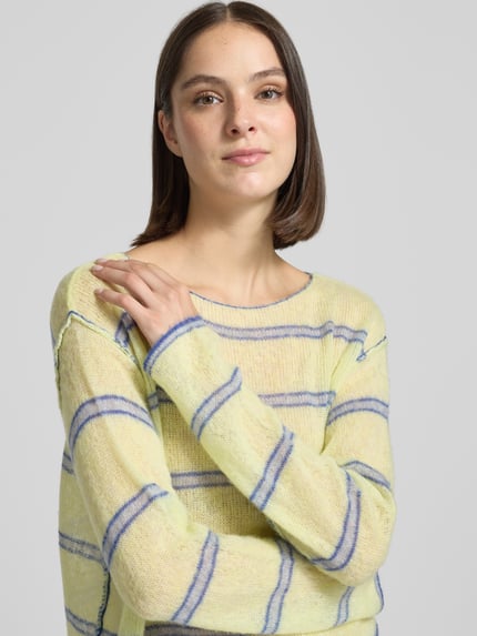 Frauenmodel trägt Relaxed Fit Strickpullover aus Lyocell-Mix Modell 'BODYROW' von American Vintage in Gelb mit blauen Streifen, U-Boot-Ausschnitt, langärmliges Design mit überschnittenen Schultern und weicher Textur, Nahaufnahme Oberkörper.