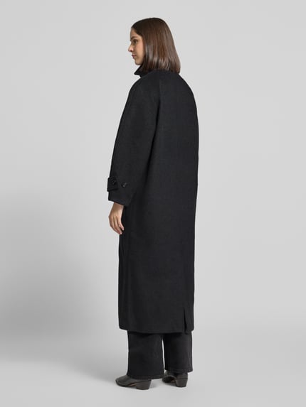 Frauenmodel trägt Mantel aus Leinen-Mix mit Stehkragen Modell 'Keaton' von Neo Noir in Schwarz, glatte Textur, Ganzkörperansicht Rückansicht. Regular Fit, Knopfleiste, Eingrifftaschen, Ärmelriegel, Rückenlänge 123 cm, Schulterbreite 38 cm, Brustweite 53 cm, Ärmellänge 59 cm.