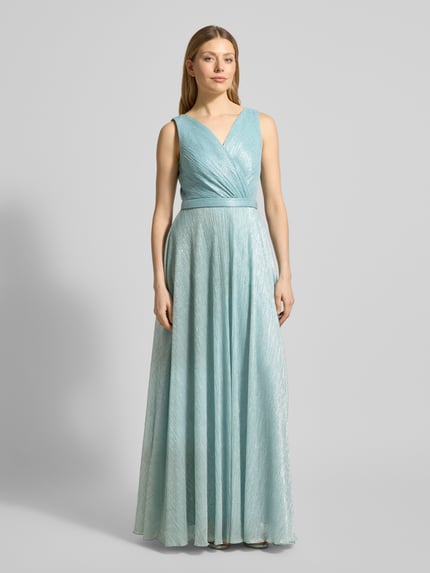 Frauenmodel trägt schimmerndes Abendkleid mit V-Ausschnitt von TROYDEN COLLECTION in Hellblau, Maxikleid mit Taillenband, Ganzkörperansicht von vorne.