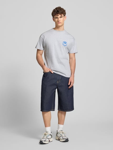 Männermodel trägt graues T-Shirt mit Logo und Rundhalsausschnitt von BLKVIS, reine Baumwolle, Regular Fit, blaue Shorts, Ganzkörperansicht von vorne.