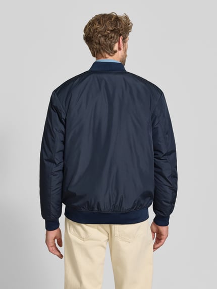 Männermodel trägt dunkelblaue Regular Fit Bomberjacke mit Baseball-Kragen Modell 'CHARLES' von Selected, Herren Bomberjacke, Ganzkörperansicht Rückansicht.