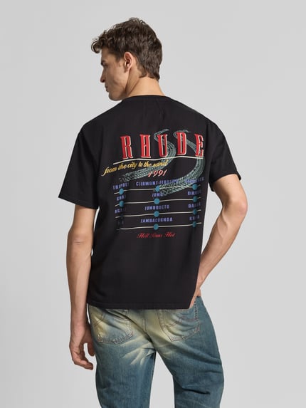 Männermodel trägt schwarzes T-Shirt mit buntem Label-Print von RHUDE, reine Baumwolle, lockerer Schnitt, Rückenansicht, Ganzkörperansicht.