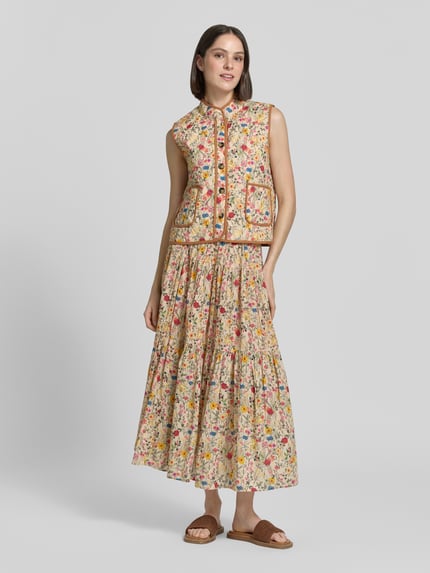 Frauenmodel trägt Steppweste im Allover-Look Modell 'Cairo' von LOLLYS LAUNDRY aus reiner Baumwolle, Regular-Fit, Knopfleiste, aufgesetzte Taschen, florale Farben und Muster, Rückenlänge bei Größe S 54 cm, Schulterbreite 37 cm, Brustweite 51 cm, Ganzkörperansicht von vorne.