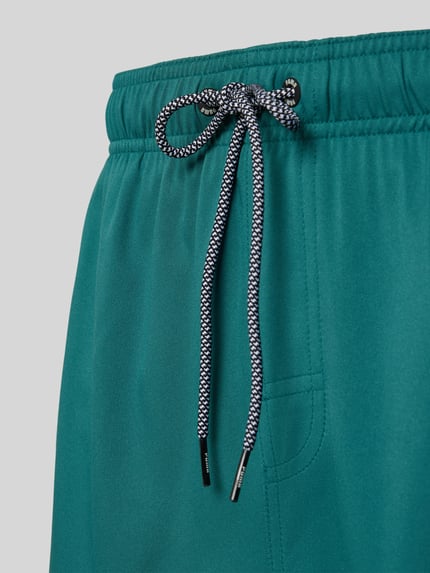 Produktfoto, spodenki kąpielowe z bocznymi kieszeniami i kieszenią z zapięciem na rzep z tyłu od PUMA, krój regular fit, elastyczny pas, zielony kolor, gładka tekstura