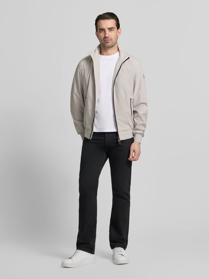 Männermodel trägt Regular Fit Jacke mit Stehkragen Modell 'Finlay' von SAVE THE DUCK, Zweiwegereißverschluss, graue Farbe, Ganzkörperansicht von vorne.