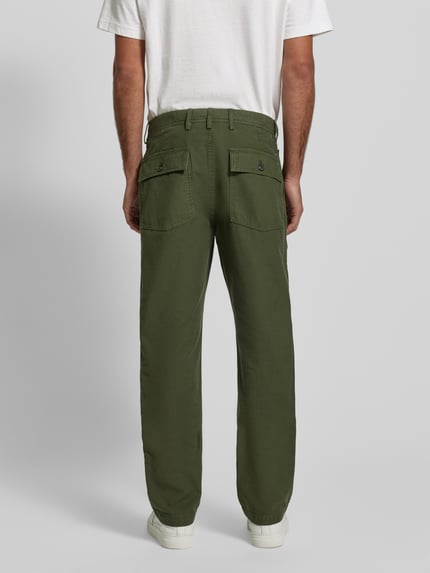 Männermodel trägt Regular Fit Chino aus reiner Baumwolle Modell 'MERCER' von Tommy Hilfiger in Unifarben, Ganzkörperansicht Rückansicht.