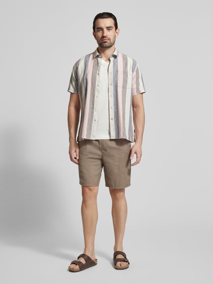 Męski model nosi Regular Fit T-Shirt aus reiner Baumwolle od Tom Tailor, kolor jednolity, krój regular fit, logo, dekolt V, krótki rękaw, jersey, bawełna, widok całej sylwetki z przodu.