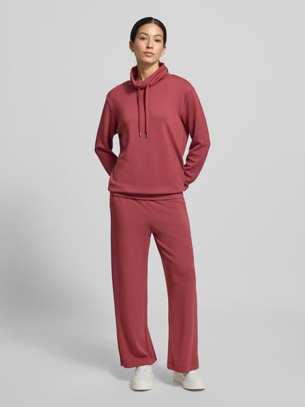 Kobiece modelka ma na sobie Bluza z tunelem Model 'Banu' od Soyaconcept, mieszanka materiałów z domieszką modalu, luźny krój, stójka, prążkowane wykończenia, widok całej sylwetki z przodu.