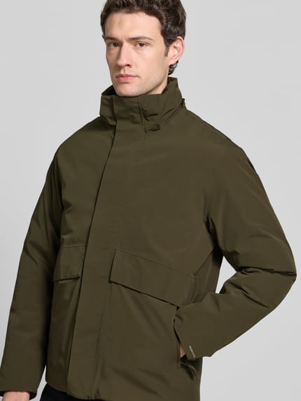 Männermodel trägt olivegrüne Jacke mit Kapuze und Pattentaschen Modell 'LAMOON' von JACK & JONES, verdeckter Reißverschluss, Nahaufnahme Oberkörper. Regular Fit, Rückenlänge 72 cm, Schulterbreite 50 cm, Brustweite 60 cm, Ärmellänge 65 cm.