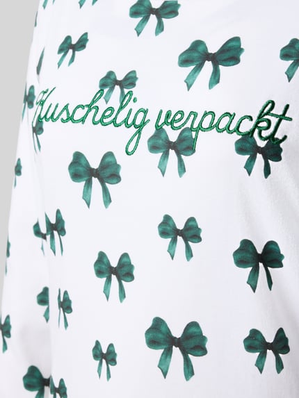 Vrouwenmodel draagt Relaxed Fit Nachthemd aus reiner Baumwolle van LOUIS & LOUISA, puur katoen, statement-stitching, ronde hals, langemouws design, witte stof met groene strikjes, detailopname bovenlichaam