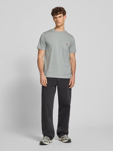 Männermodel trägt Regular Fit T-Shirt mit Logo-Patch von Carhartt Work In Progress in Grau aus Reine Baumwolle mit Brusttasche, Rundhalsausschnitt, Rückenlänge bei Größe M 70 cm, Ganzkörperansicht von vorne.