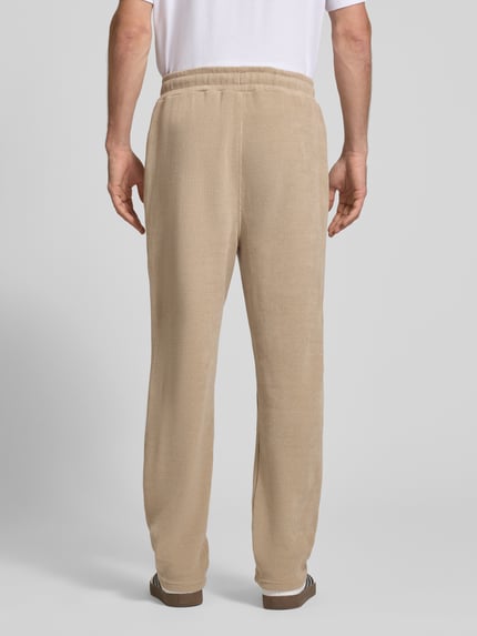 Männermodel trägt Wide Fit Sweatpants mit Label-Detail Modell 'Mezzano' von PEGADOR in Beige, elastischer Material-Mix, Rückansicht, Ganzkörperansicht von hinten.