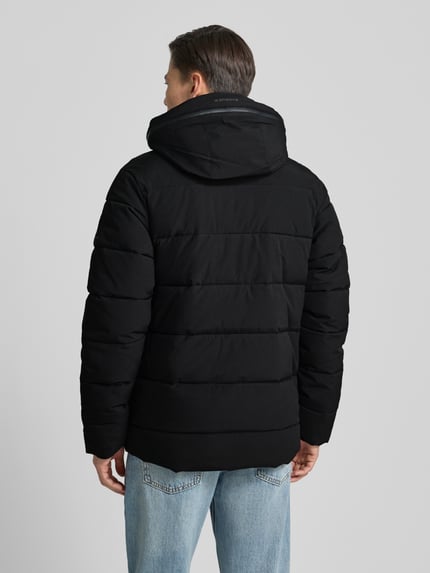 Männermodel draagt zwarte Steppjacke met kapuze model 'BIXBY' van Icepeak, rechte pasvorm, ruglengte 78 cm, Ganzkörperansicht Rückansicht.