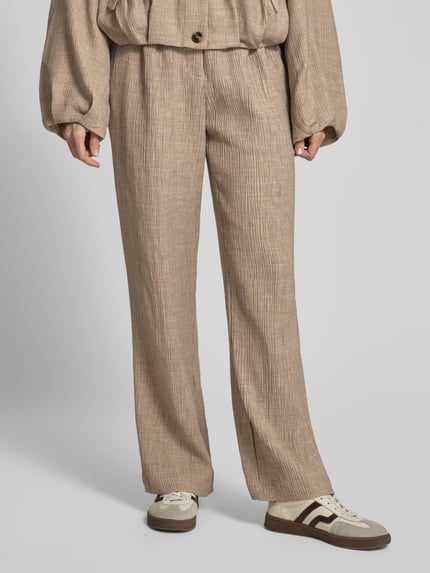 Frauenmodel trägt Stoffhose aus Viskose-Mix mit elastischem Bund von YAS, Wide-Leg-Pants Modell RINA, beige, strukturierte Textur, Nahaufnahme Unterkörper.