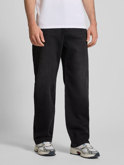 Mężczyzna nosi Baggy Jeans in schwarzer Waschung und klassischem 5-Pocket-Design od REVIEW, Mieszanka bawełny i elastanu, krój baggy, czarny odcień, 5 kieszeni, zapięcie na guzik i zamek błyskawiczny, Szerokość w rozmiarze 32: 42 cm, Długość wewnętrzna nogawki: 76 cm, zdjęcie całej sylwetki z przodu