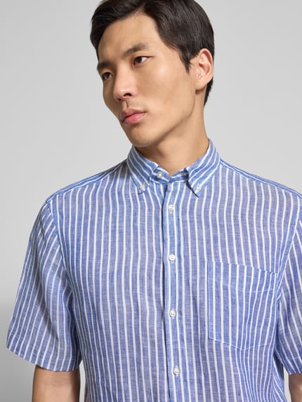 Männermodel trägt Regular Fit Freizeithemd aus Leinen von Christian Berg Men, blau-weiß gestreift, Button-Down-Kragen, Nahaufnahme Oberkörper.
