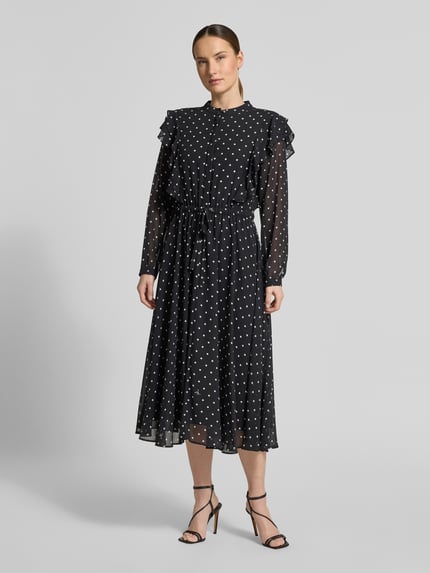 Frauenmodel trägt Midikleid im Allover-Look mit Bindegürtel von JOOP!, schwarze A-Linie mit Rundhalsausschnitt, Volants, transparente Ärmel, Ganzkörperansicht von vorne. Rückenlänge bei Größe 36: 120 cm, Brustweite: 47 cm, Ärmellänge: 63 cm.