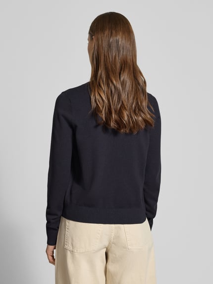 Frauenmodel trägt Strick-Cardigan aus Viskose-Mix mit langen Ärmeln von Review, Regular-Fit, Knopfverschluss, Rippbündchen, Beige-Hose, Ganzkörperansicht Rückansicht.