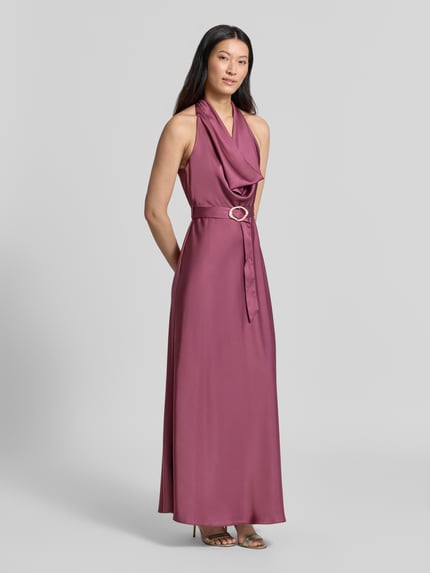 Frauenmodel trägt Abendkleid mit Neckholder von Rinascimento in Rosa, glatter Stoffmix, tailliert, Stoffgürtel, Ganzkörperansicht von vorne.