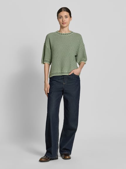 Vrouwenmodel draagt gebreide pullover met 1/2-mouwen model 'Catina Pilla' van MSCH Copenhagen in katoenmix, recht model, ronde hals, schouderpartijen, ruglengte maat S/M 54 cm, mouwlengte 34 cm, groene en witte structuur, rechte vormen, fijne textuur, volledige lichaamsweergave van voren.