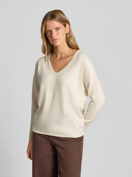 Modelka kobieca nosi Relaxed Fit Pullover mit V-Ausschnitt od ONLY, kremowy sweter z dekoltem w serek, gładka dzianina, widok całej sylwetki z przodu, damski sweter ONLY