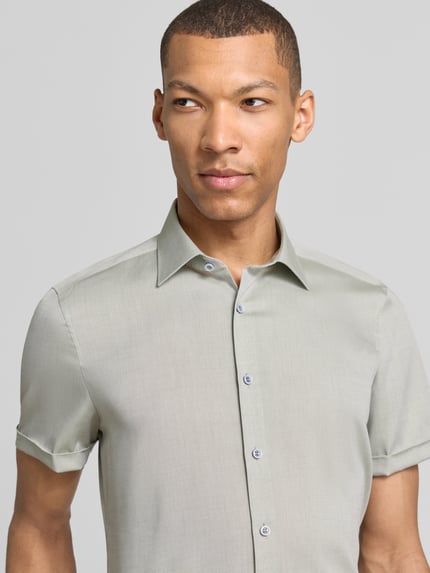 Männermodel trägt Slim Fit Business-Hemd mit kentkraag von OLYMP Level Five uit puur katoen met knoopsluiting, omslag bij de mouwen, nahaufnahme oberkörper. Ruglengte bij maat 40: 70 cm, schouderbreedte: 40 cm, mouwlengte: 24 cm.