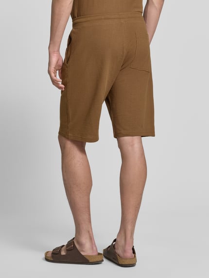 Männermodel trägt Relaxed Fit Sweatshorts aus reiner Baumwolle Modell 'DETROIT' von s.Oliver RED LABEL, Optik: Unifarben, Passform: Relaxed-Fit, fein strukturiertes Muster, Tunnelzug, Bundabschluss: elastisch, seitliche Eingrifftaschen, Gesäßtasche, Material: reine Baumwolle, Ganzkörperansicht Rückansicht.