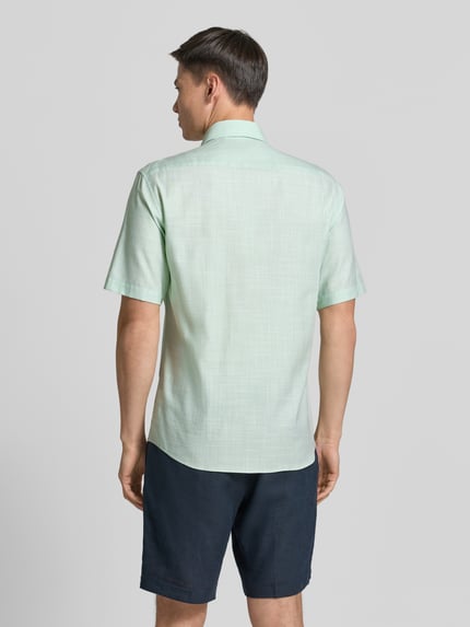 Männermodel trägt Modern Fit Business-Hemd mit Kentkragen von ETERNA aus Baumwoll-Lyocell-Mix, 1/2-Arm, Rückansicht, Ganzkörperansicht.