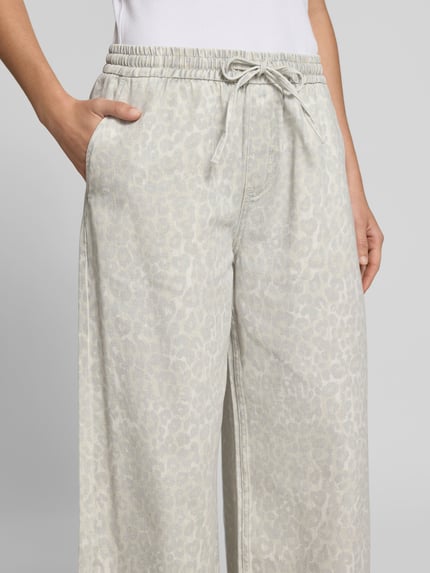 Frauenmodel trägt Stoffhose mit Allover-Animal-Print von Lala Berlin aus Reiner Baumwolle, Wide-Fit, elastischer Bund mit Tunnelzug, seitliche Eingriffstaschen, dezente graue Musterstruktur, Nahaufnahme Oberkörper.