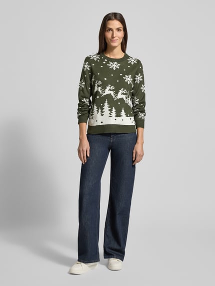 Frauenmodel trägt zielony Strickpullover mit Rundhalsausschnitt Modell 'SNOWI' od Vila, wzór śnieżynki i drzewa, dopasowany krój, całkowity widok z przodu.