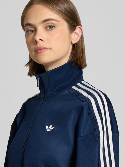 Frauenmodel trägt Oversized Sweatjacke aus Baumwoll-Mix Modell 'LACE OVERSIZED' von adidas Originals in Dunkelblau mit weißen Details, Nahaufnahme Oberkörper. Damen Sweatjacke von adidas Originals
