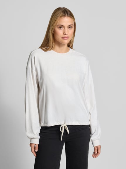 Modelka nosi Relaxed Fit bluzkę z długim rękawem z czystej bawełny od DRYKORN, tunel w pasie, prążkowane ściągacze, widok z przodu,
