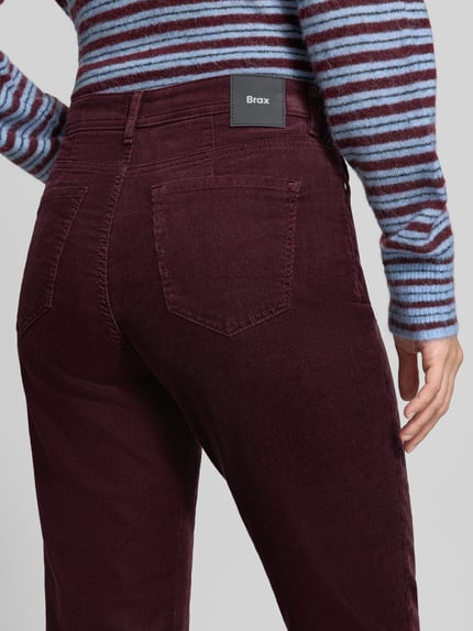 Frauenmodel trägt Schmale Hose aus Baumwoll-Lyocell-Mix Modell 'CAROLA' von Brax in Dunkelrot, sichtbare Cordstruktur, Nahaufnahme Rückansicht, Damen Schmale Hose von Brax