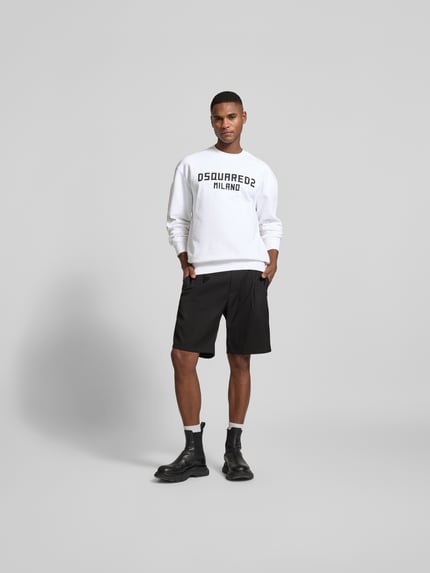 Männermodel trägt Cool Fit Sweatshirt aus reiner Baumwolle von Dsquared2 in Weiß mit schwarzem Label-Print, Ganzkörperansicht von vorne.