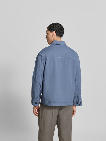Männermodel trägt Relaxed Fit Hemdjacke aus Baumwolle von ANNARR in Blau mit Umlegekragen, Rückenlänge 69 cm, Ganzkörperansicht Rückansicht.