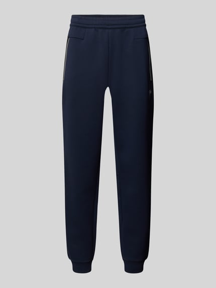 Produktfoto, dunkelblaue Sweatpants mit geradem Schnitt, elastischem Bund, Reißverschlusstaschen und gerippten Abschlüssen, Modell 'TRAIN PREMIUM SHIELD' von EA7 Emporio Armani, elastischer Material-Mix mit Viskose-Anteil