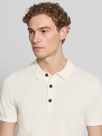 Męski model nosi Regular Fit Poloshirt aus reiner Baumwolle od s.Oliver RED LABEL, efekt: jednolity kolor, imitacja dzianiny, krótki rękaw, kołnierzyk polo, drobny splot, bawełna, zapięcie: krótka listwa guzikowa, zakończenie: prążkowane, kolor jasny, powierzchnia o delikatnej strukturze, ujęcie: zbliżenie na górę ciała