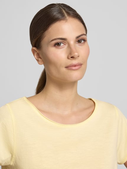 Frauenmodel trägt T-Shirt mit Rundhalsausschnitt von Christian Berg Woman aus Reine Baumwolle, Regular-Fit, Rollsaum, Nahaufnahme Oberkörper.