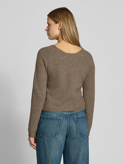 Frauenmodel trägt Pullover mit Wickeloptik von PIECES in Braun mit feiner Stricktextur zu blauen Jeans, Ganzkörperansicht Rückansicht.