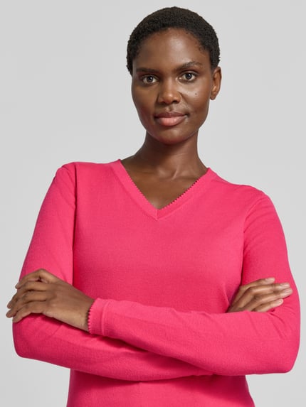 Frauenmodel trägt Pullover aus Viskose-Mix mit V-Ausschnitt von Christian Berg Woman, pink, gerader Schnitt, Nahaufnahme Oberkörper.