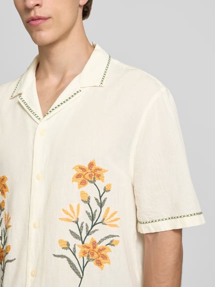Männermodel trägt Relaxed Fit Freizeithemd mit Motiv-Stitching von REVIEW, Baumwoll-Mix, gelb-grüne Stickerei, Nahaufnahme Oberkörper.