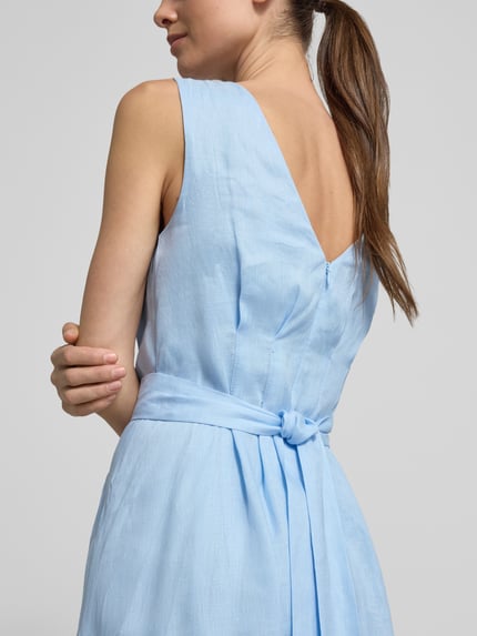 Frauenmodel trägt Cocktailkleid aus Leinen Modell 'Rosie' von Forever New, hellblau, tailliert, strukturierte Oberfläche, Nahaufnahme Oberkörper Rückansicht.