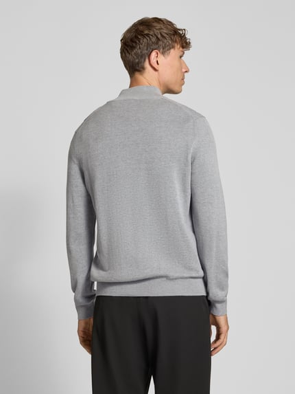Männermodel trägt Pullover mit halblangem Reißverschluss von LACOSTE in Grau, Feinstrick mit Struktur, Logo-Detail, Ganzkörperansicht Rückansicht.